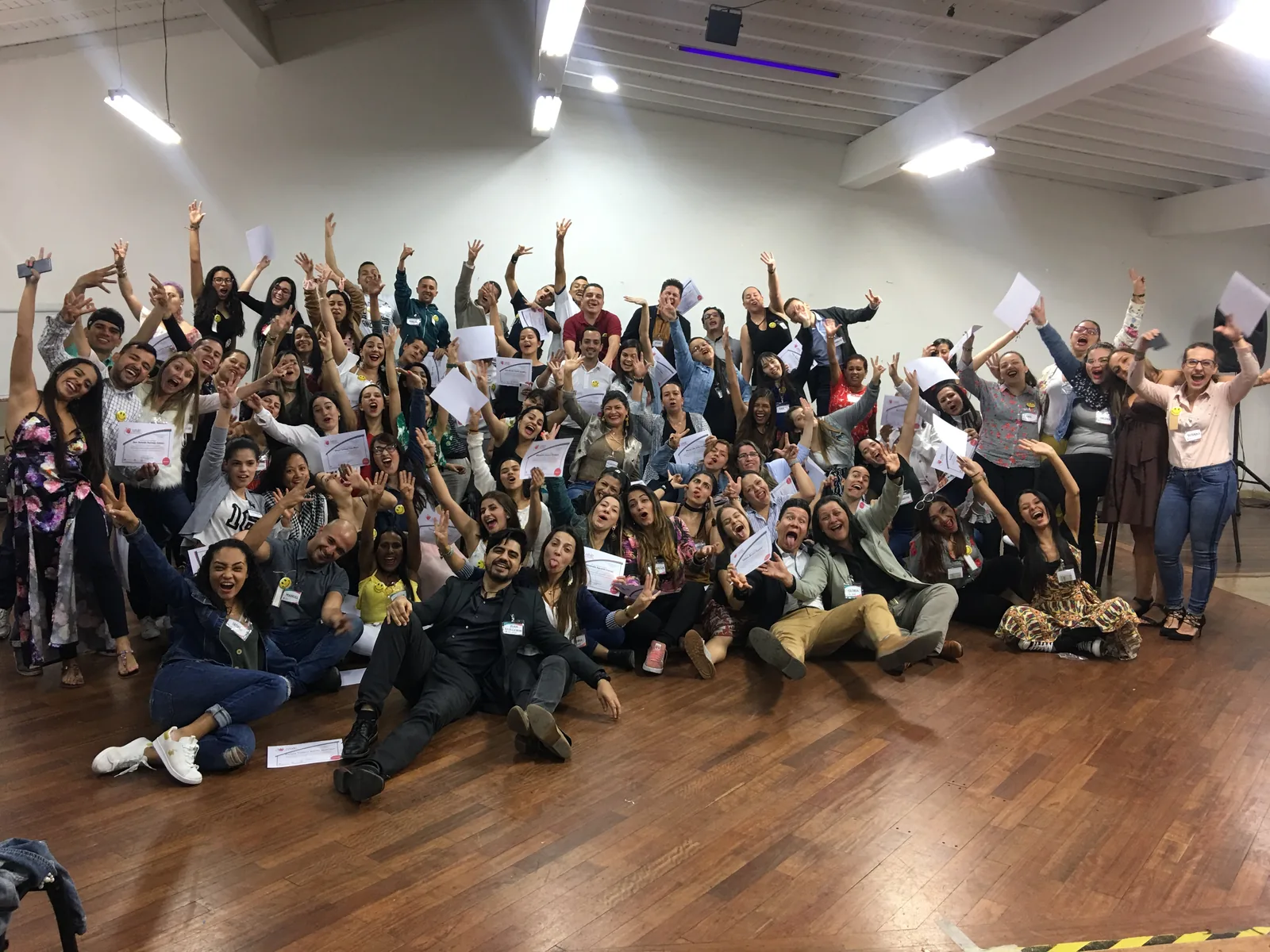 Grupo de personas adultas con los brazos levantados durante una actividad en sala